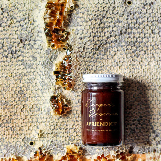 Jar of WellNest Keeper's Reserve 15+ Manuka Honey in a 160g glass container with a white lid, showing the honey's rich amber color.