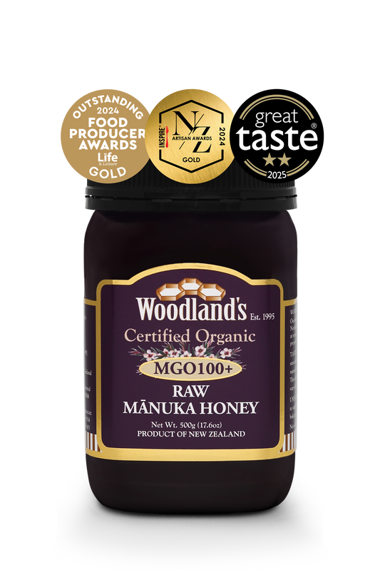 Jar of WellNest MGO100+ Organic Raw Manuka Honey with gold label, 500g, showcasing the rich, golden honey inside.