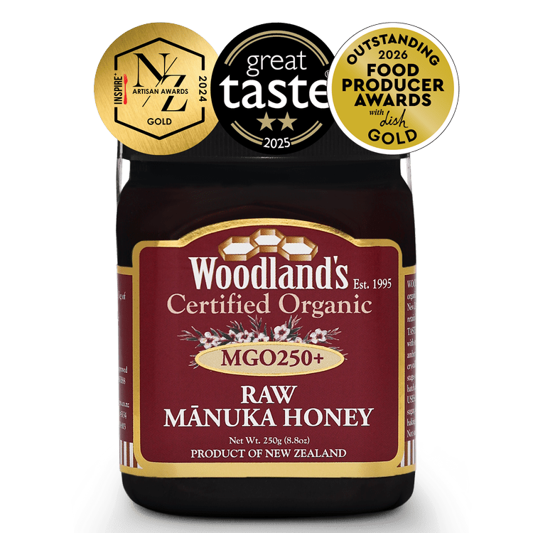 Jar of WellNest MGO250+ Organic Raw Manuka Honey with OFPA Silver and Gold labels, 250g, showcasing golden honey inside.