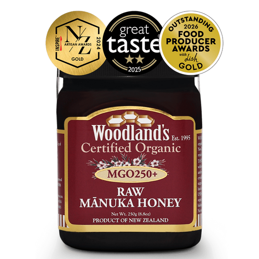Jar of WellNest MGO250+ Organic Raw Manuka Honey with OFPA Silver and Gold labels, 250g, showcasing golden honey inside.
