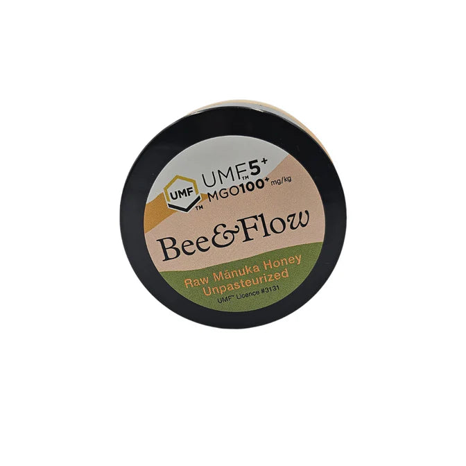Jar of WellNest Bee & Flow Raw Manuka Honey UMF 5+ with MGO 100+ in a glass jar, showing the honey’s golden color and label.