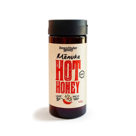 Jar of WellNest Manuka Hot Honey 325g, golden Manuka honey with a smooth, viscous texture and natural honeycomb pattern.
